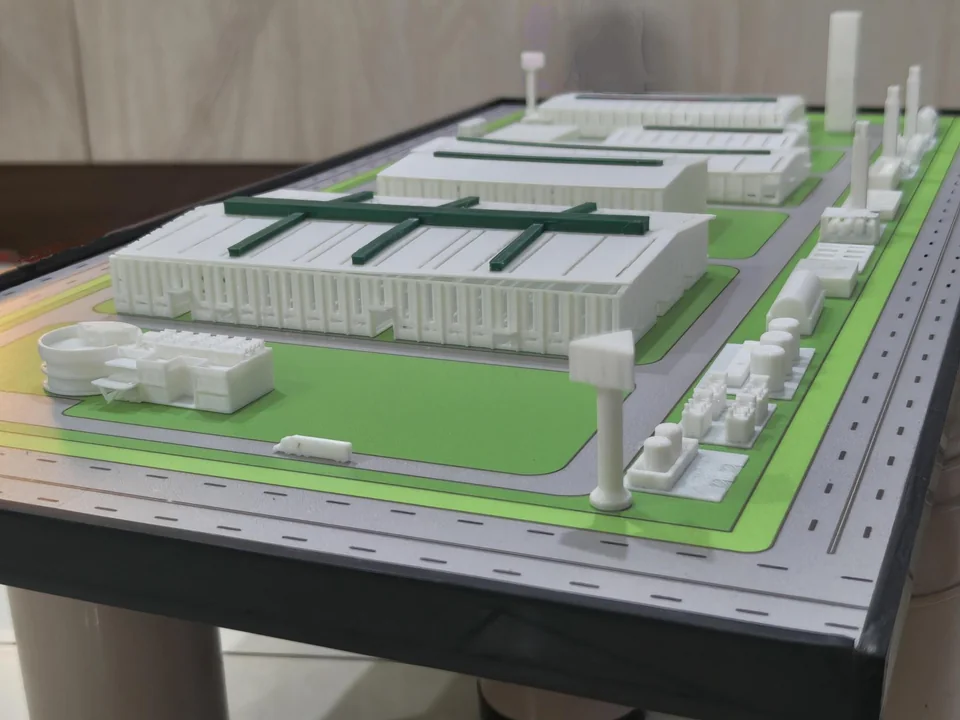 Industrial-site model with white buildings, grey roads and green areas on a rectangular base